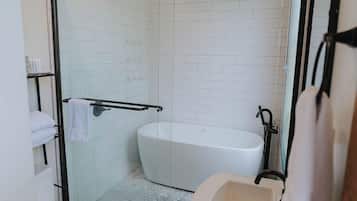 A modern bathroom with a glass-enclosed shower, a white bathtub, and a sink.
