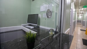 Una recepción con un computador, un reloj y una planta en maceta.