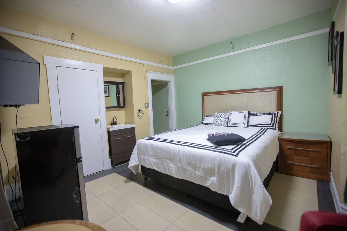A bedroom with a bed, a television, a desk, and a chair.
