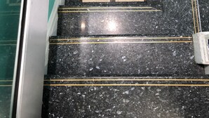 Una escalera con escalones de mármol negro y patrones geométricos en la pared.
