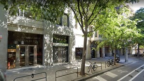 Une vue d’une rue avec un bâtiment portant l’inscription « DIPUTATIO 119 » et un vélo garé sur le trottoir.