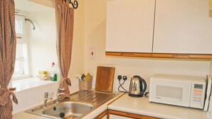 A compact kitchen with a sink, a kettle, and a microwave.