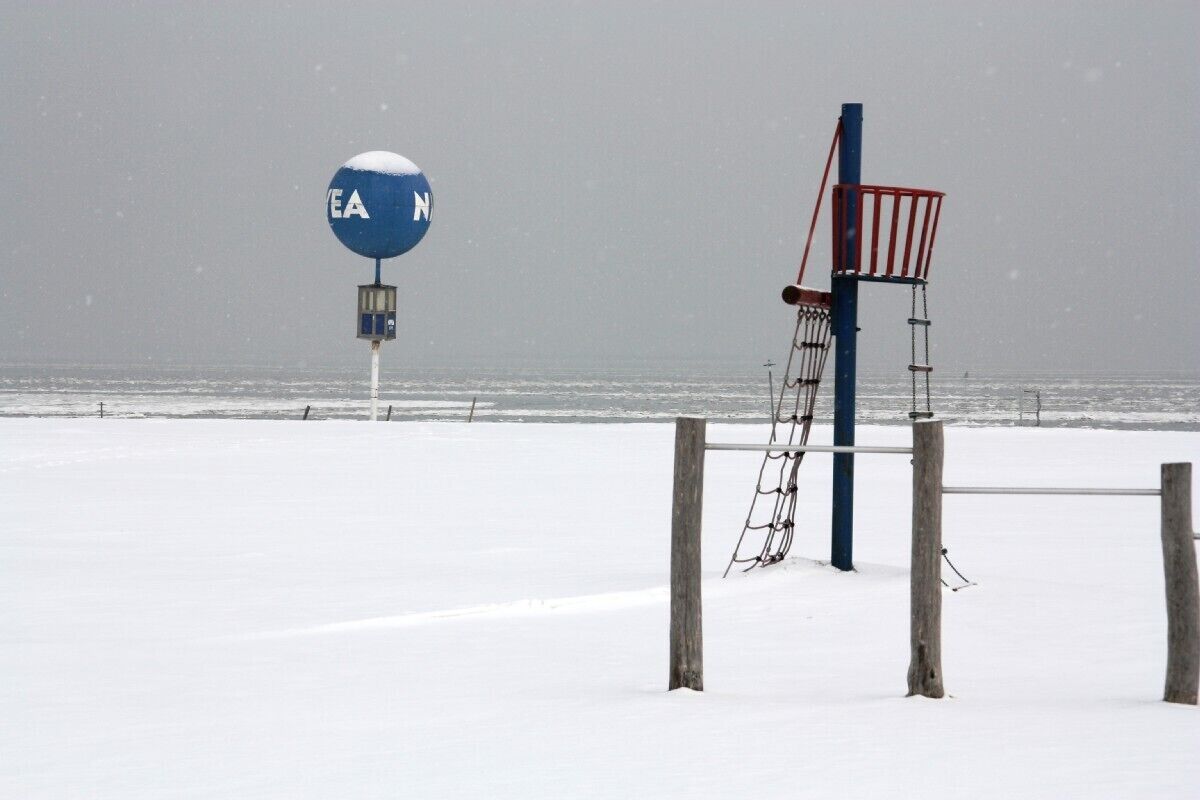 A beach with a lifeguard tower and a blue sign with "EA" and "N" on it.