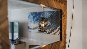 A modern room with a large mirror reflecting a wall-mounted artwork and a spiral light fixture.