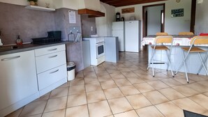 Una cocina con armarios blancos, estufa, refrigerador y comedor con sillas.