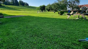 Un parque con césped, un área de juegos, bancos y árboles.
