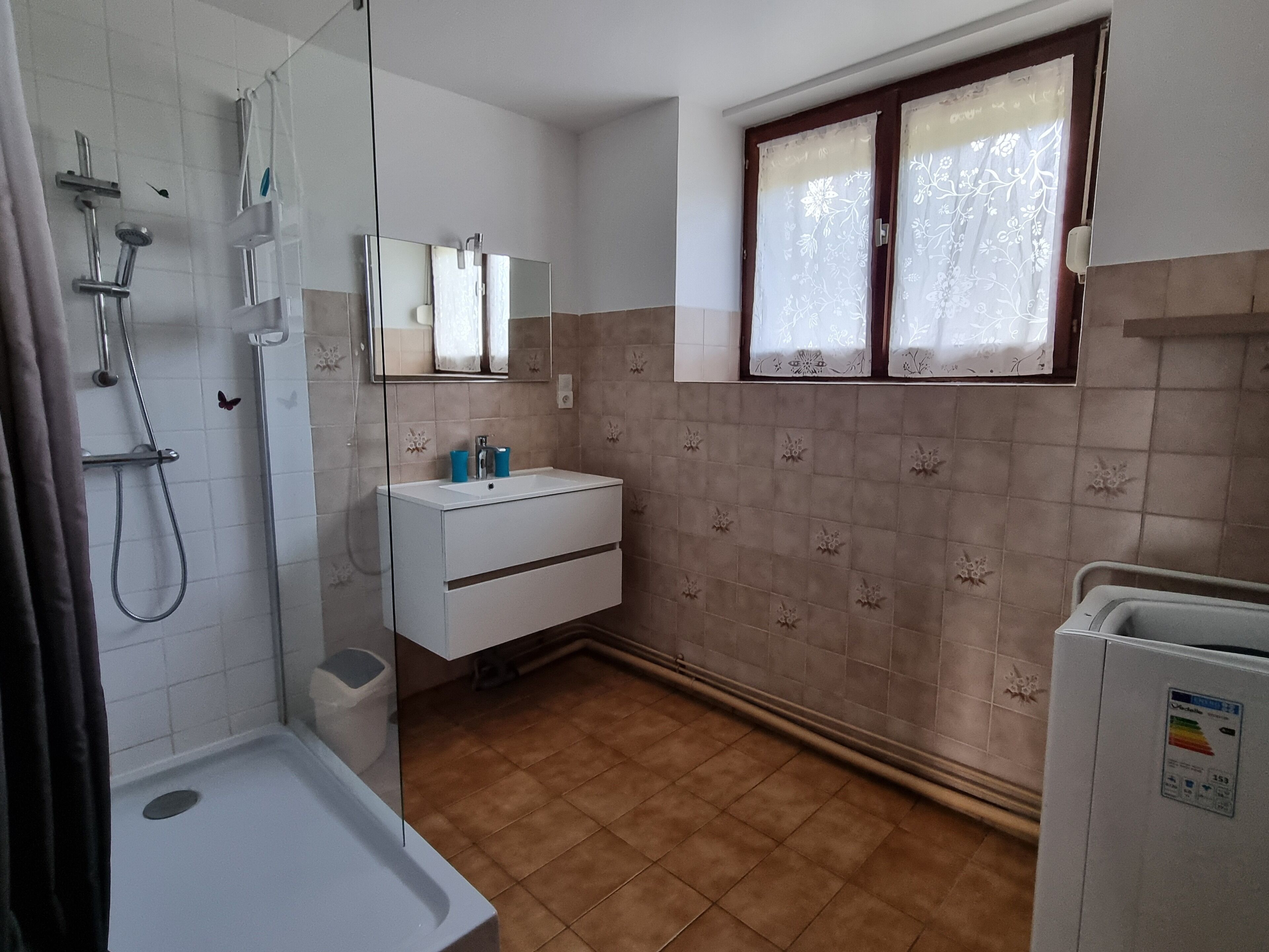 Un baño con ducha, lavabo y ventana.