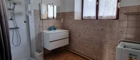 A bathroom with a shower, sink, and window.