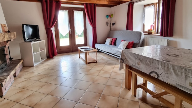 Una habitación acogedora con sofá, televisión sobre un mueble bajo, una mesita y una cama con diseño de reloj.