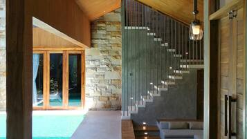 A modern interior with a stone wall, wooden flooring, a staircase, and a pool.