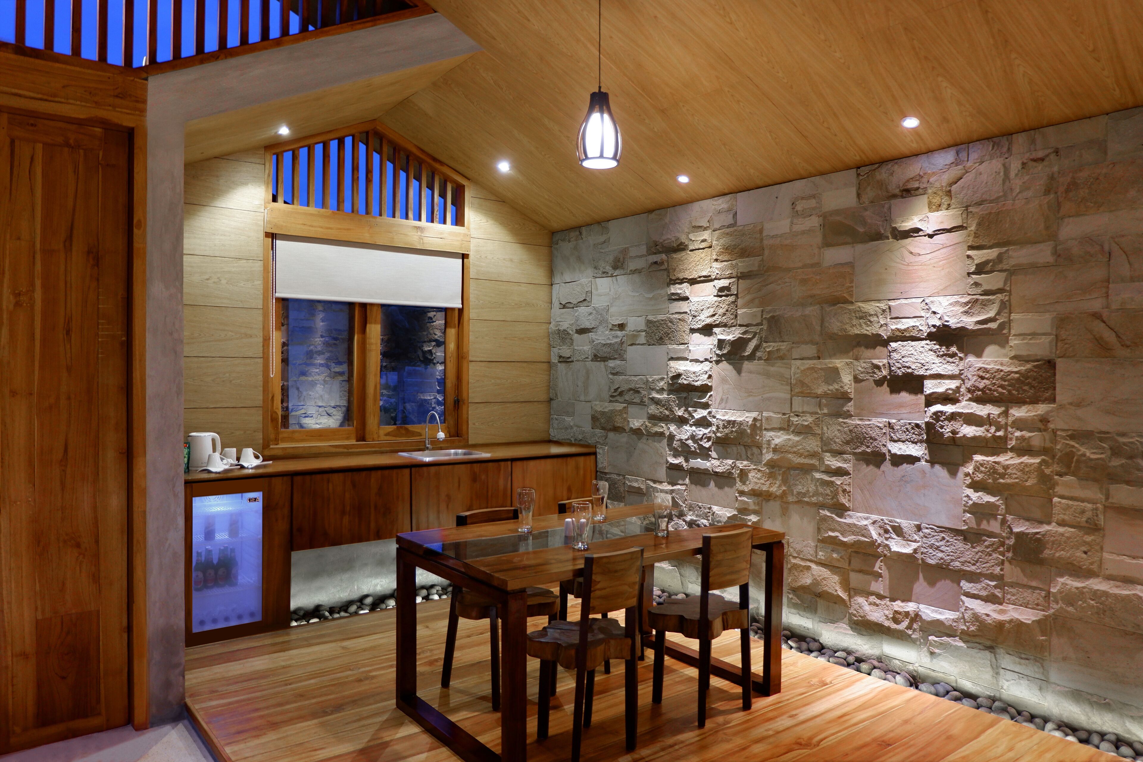 A wooden dining table with chairs, a stone wall, and a wooden ceiling.