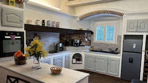 A modern kitchen with white cabinetry, a central island, and a built-in oven.