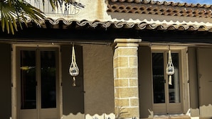 A building with a tiled roof, a stone pillar, and two doors with hanging light fixtures.