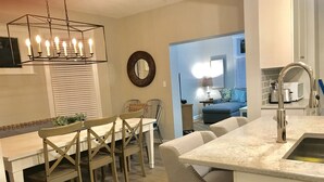 A modern kitchen with a dining area, featuring a chandelier, a round mirror, and a kitchen island with a sink. - Urban Oasis 3 Miles to Cincy Sleeps 12 (Dayton)