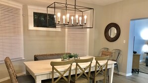 A dining area with a white table, wooden chairs, and a hanging light fixture. - Urban Oasis 3 Miles to Cincy Sleeps 12 (Dayton)