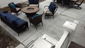 An outdoor patio with a round table, wicker furniture, and a grill area. - Urban Oasis 3 Miles to Cincy Sleeps 12 (Dayton)
