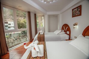 Habitación de hotel con dos camas, un balcón y vistas a un parque.