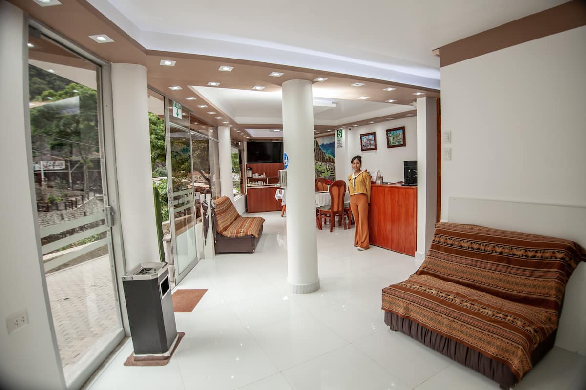 Habitación de hotel con balcón, sofá, escritorio y área de recepción.