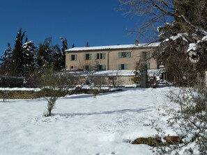 Un edificio con muro de piedra y suelo cubierto de nieve.