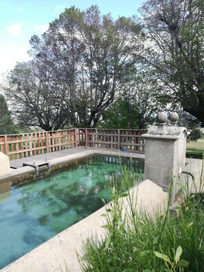 Una piscina rectangular con cubierta de madera y barandilla de piedra.