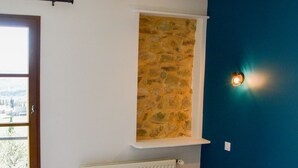 Une chambre à coucher avec un lit, une fenêtre, un radiateur et un mur en pierre.