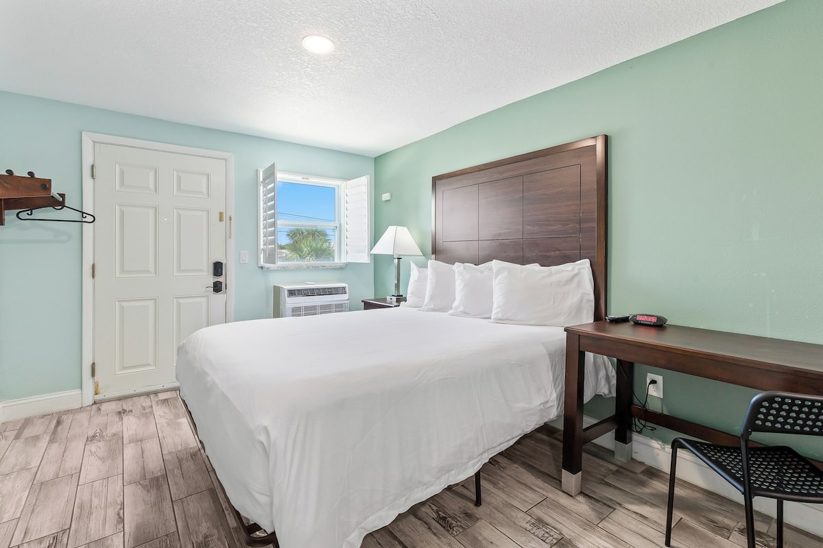 A bedroom with a bed, a desk, and a chair.