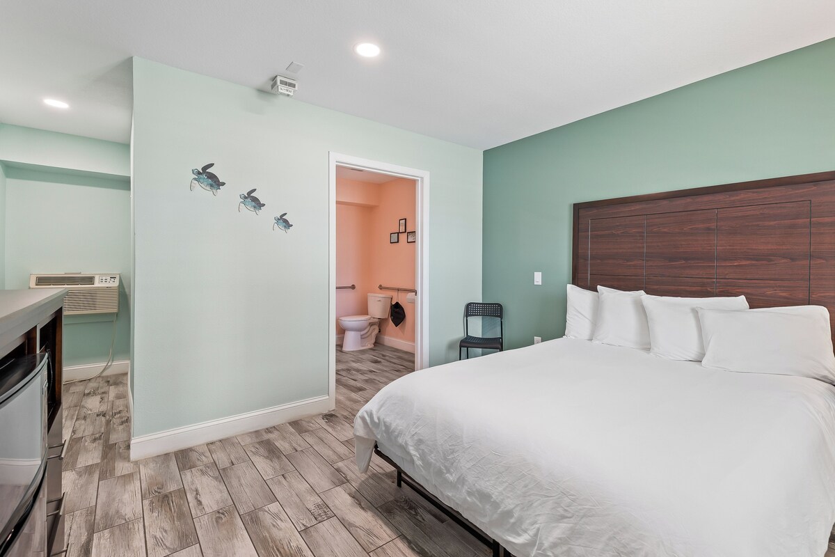 Een slaapkamer met een bed, een dressoir en een badkamer die door een geopende deur zichtbaar is.