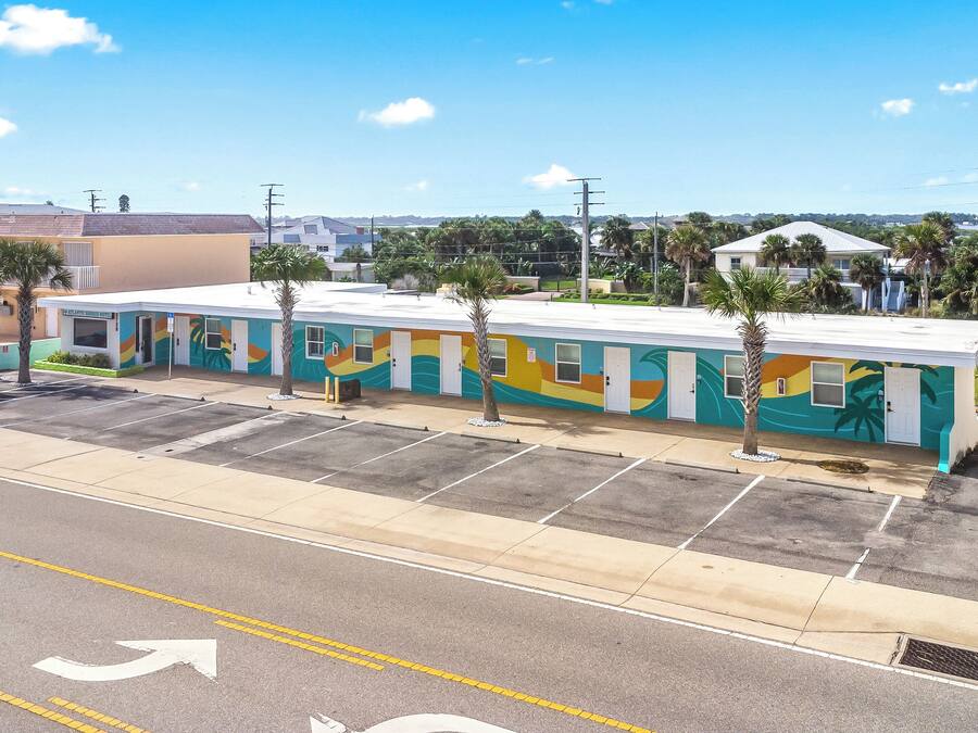 A motel with a colorful exterior, a parking lot, and a clear sky.