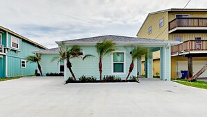 A single-story house with a covered porch, a garage, and a small front yard with palm trees. - PRIVATE Heated POOL!!!  Endless Summer is just blocks from the beach!! (Port Aransas)