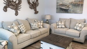 A living room with two sofas, patterned cushions, a coffee table, a lamp, and wall art. - PRIVATE Heated POOL!!!  Endless Summer is just blocks from the beach!! (Port Aransas)