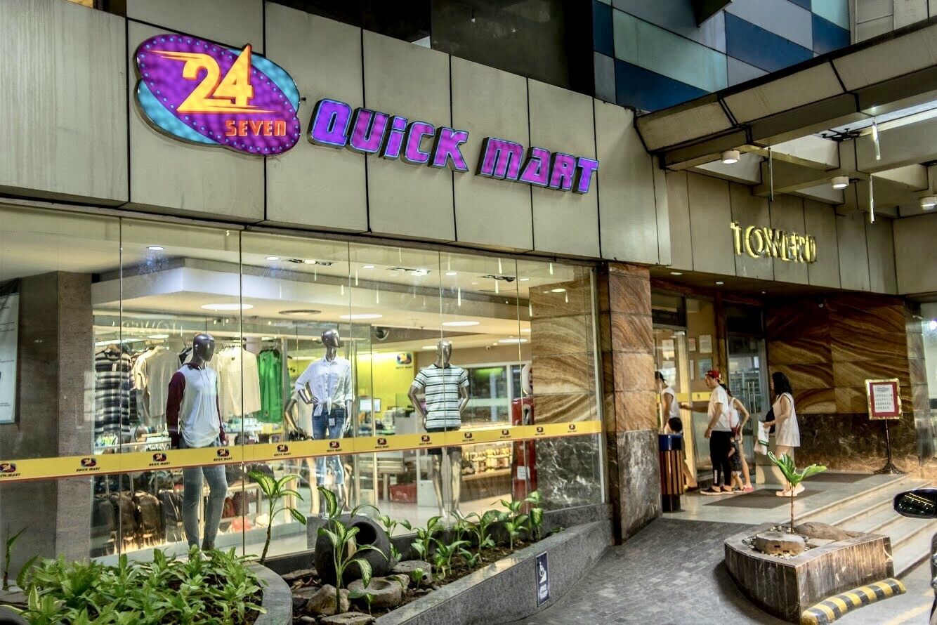 Een 24 SEVEN QUICK MART winkel met mannequins waarop kleding wordt gepresenteerd.