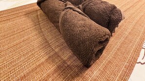 Una habitación de hotel con cama, almohadas, mesita de noche y lámpara.