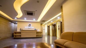 Zona de recepción con un mostrador curvo, un sofá y una mesa de madera.