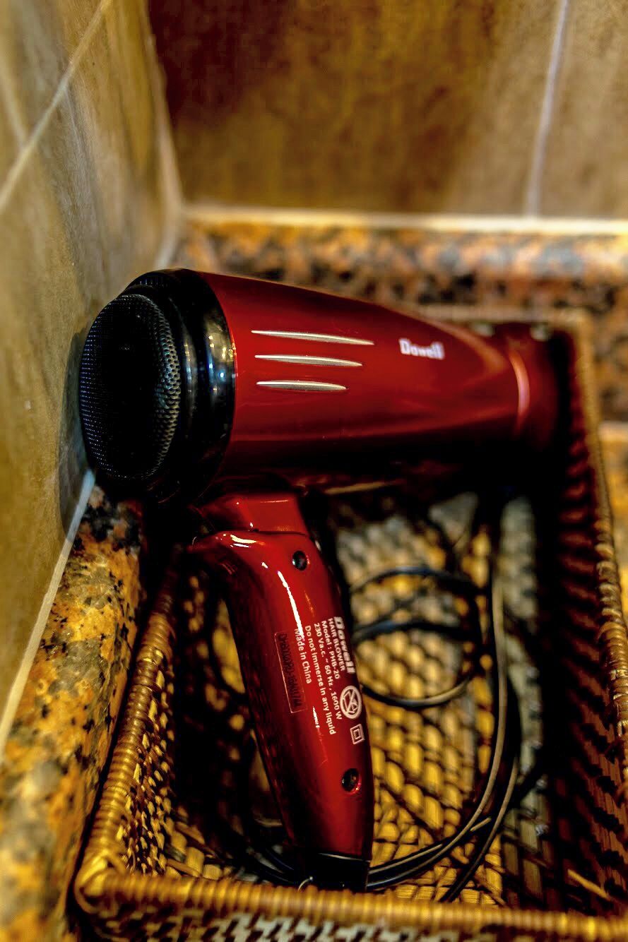 A red hair dryer in a wicker basket.