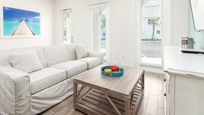 Ein modernes Wohnzimmer mit einem weißen Sofa, einem Holztisch mit einer bunten Schüssel und einem Deckenventilator.