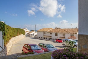 A residential street with parked cars, houses with tiled roofs, and a clear sky. - Riviera Playa | Charming Apartment with Sea Views, Terrace & Pools (Mijas Costa)