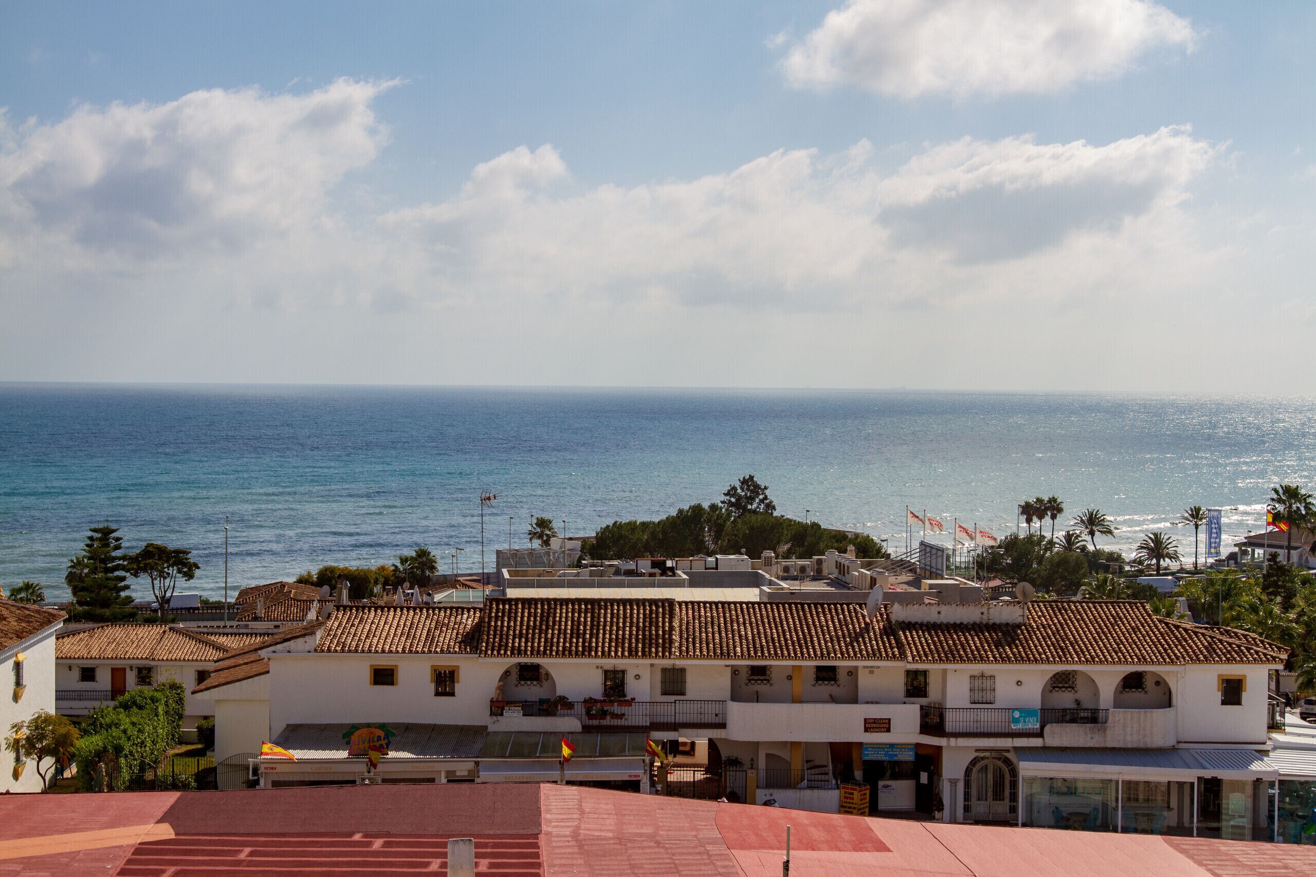 Un pueblo costero con edificios, cielo despejado y el mar.