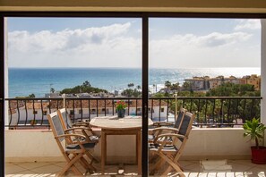 Enjoy the ocean view from this balcony with a table for four and a potted plant.