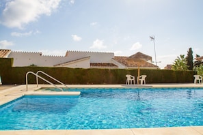 A swimming pool with a clear blue water surface, surrounded by a low hedge and white chairs. - Riviera Playa | Charming Apartment with Sea Views, Terrace & Pools (Mijas Costa)
