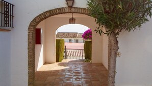 An arched entrance with a tiled floor, a small tree, and a lamp post. - Riviera Playa - Costa del Sol - Charming apartment with Sea View (Mijas Costa)