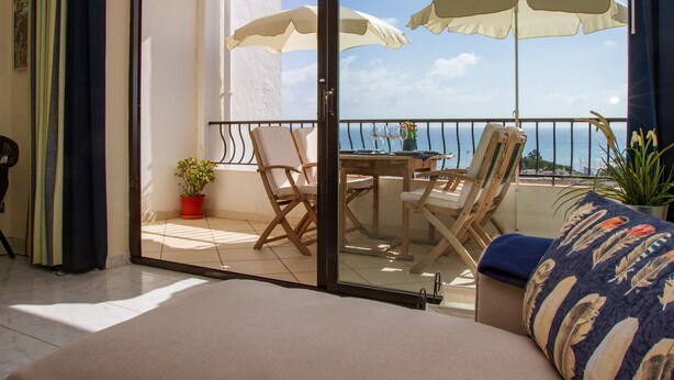 A balcony with a table, chairs, and umbrellas, overlooking a body of water. - Riviera Playa - Costa del Sol - Charming apartment with Sea View (Mijas Costa)