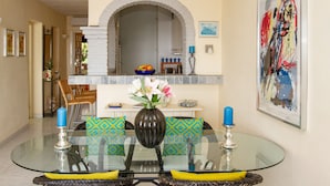 A dining area with a glass table, wicker chairs, patterned cushions, a vase with flowers, and a blue candle holder. - Riviera Playa - Costa del Sol - Charming apartment with Sea View (Mijas Costa)