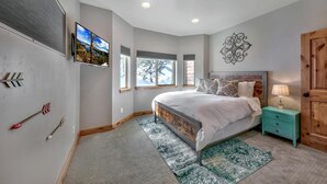 Una camera da letto con un letto, un comodino, una TV a muro e un elemento decorativo.