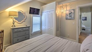 Quarto com cama, penteadeira, televisão e obras de arte.