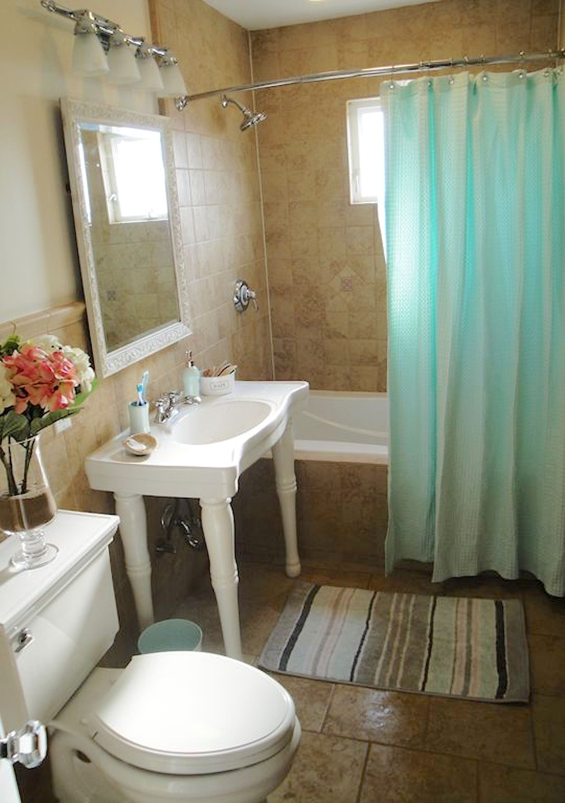 A bathroom with a white sink, mirror, toilet, and bathtub.