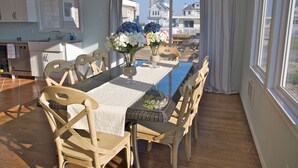 Een eethoek met een lange tafel, stoelen en een bloevas.