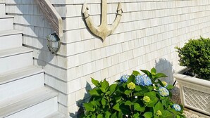 Een huis met een nummer '23' bord, een decoratief anker en een trap naar de ingang.
