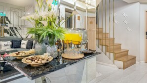 A modern kitchen with marble countertops, a central island with decorative items, and a staircase with wooden steps. - Tori Prestige Bangkok Hotel (Bangkok)