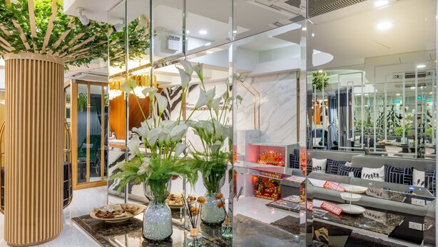 A modern interior with a reception desk, a large potted plant, and a display of furniture. - Tori Prestige Bangkok Hotel (Bangkok)