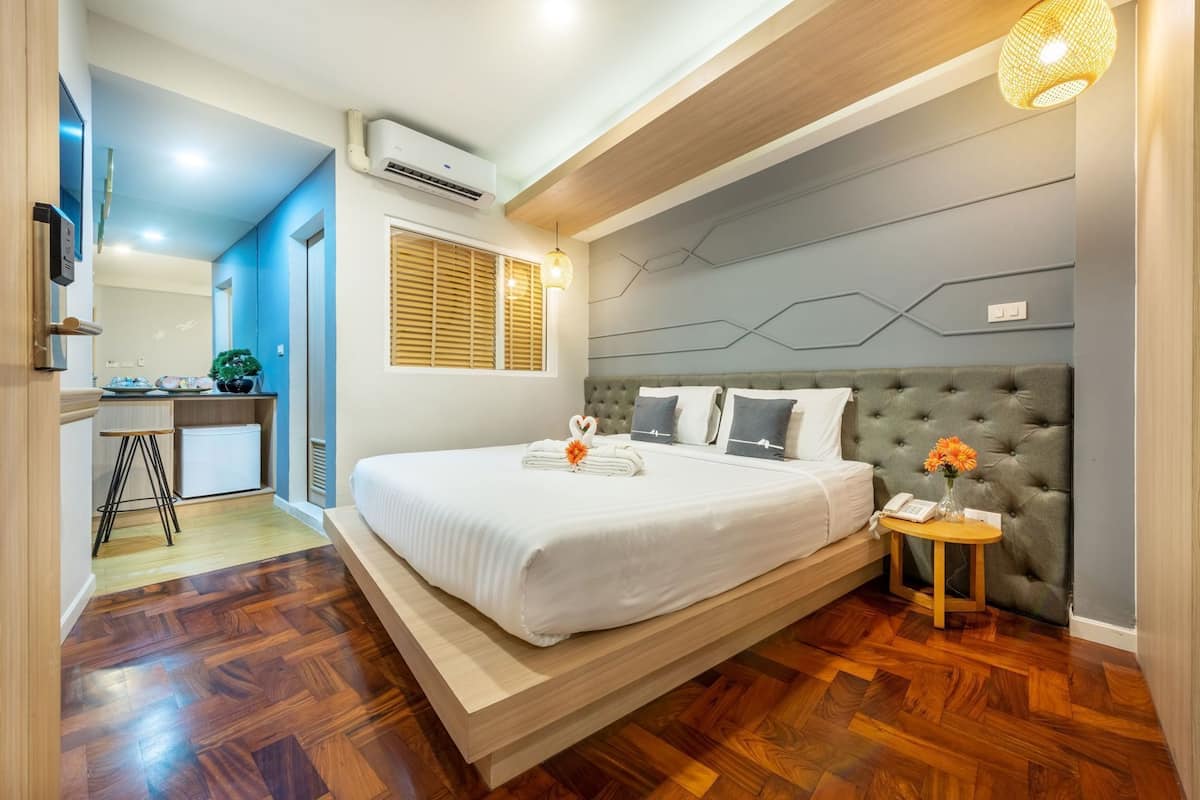 Une chambre d’hôtel moderne équipée d’un lit, d’une table de chevet et d’un petit bureau.